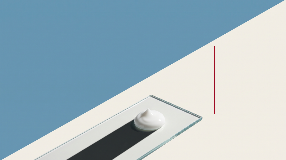 Una goccia densa di crema bianca su una lastra di vetro, su fondo diviso da una diagonale, metà azzurra e metà bianco osso