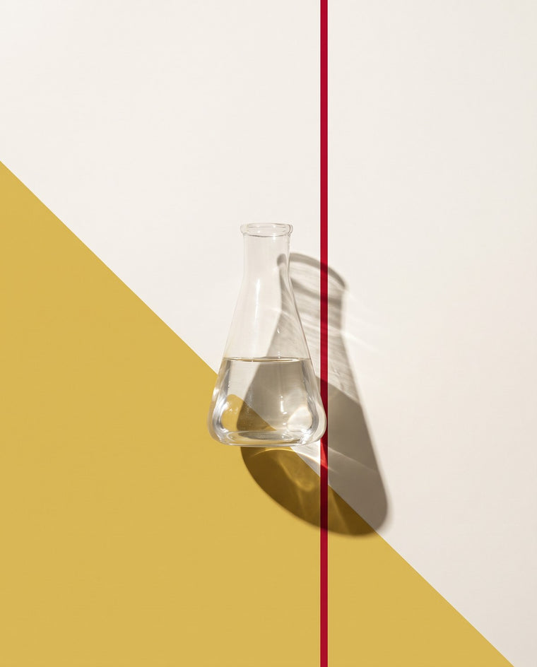 Beuta da laboratorio in vetro con liquido trasparente su campo oro